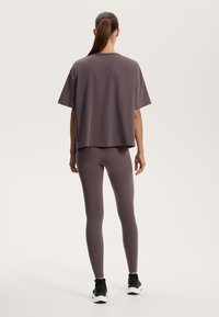 Överdimensionerad grå t-shirt med korta ärmar i kombination med matchande åtsittande leggings. Outfiten har en mjuk textur och en avslappnad passform.