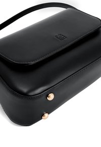 Bolso de mano de cuero negro con cierre de solapa, que presenta acentos de hardware en tono dorado y una textura suave y elegante. Forma rectangular compacta.
