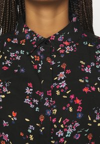 Černá květinová košile s multicolor květinovými vzory, s tlačítkovým límečkem a strukturovanou tkaninou s drobnými, živými detaily.