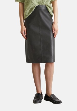 Jupe crayon en cuir noir avec une texture lisse, un design à hauteur de genoux et une silhouette ajustée ; accompagnée de mocassins plats noirs.
