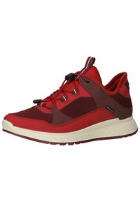 Scarpe da atletica rosse con una combinazione di materiali lisci e testurizzati, pannelli in rete e una suola bianca. Presentano un sistema di lacci a toggle per la regolazione.
