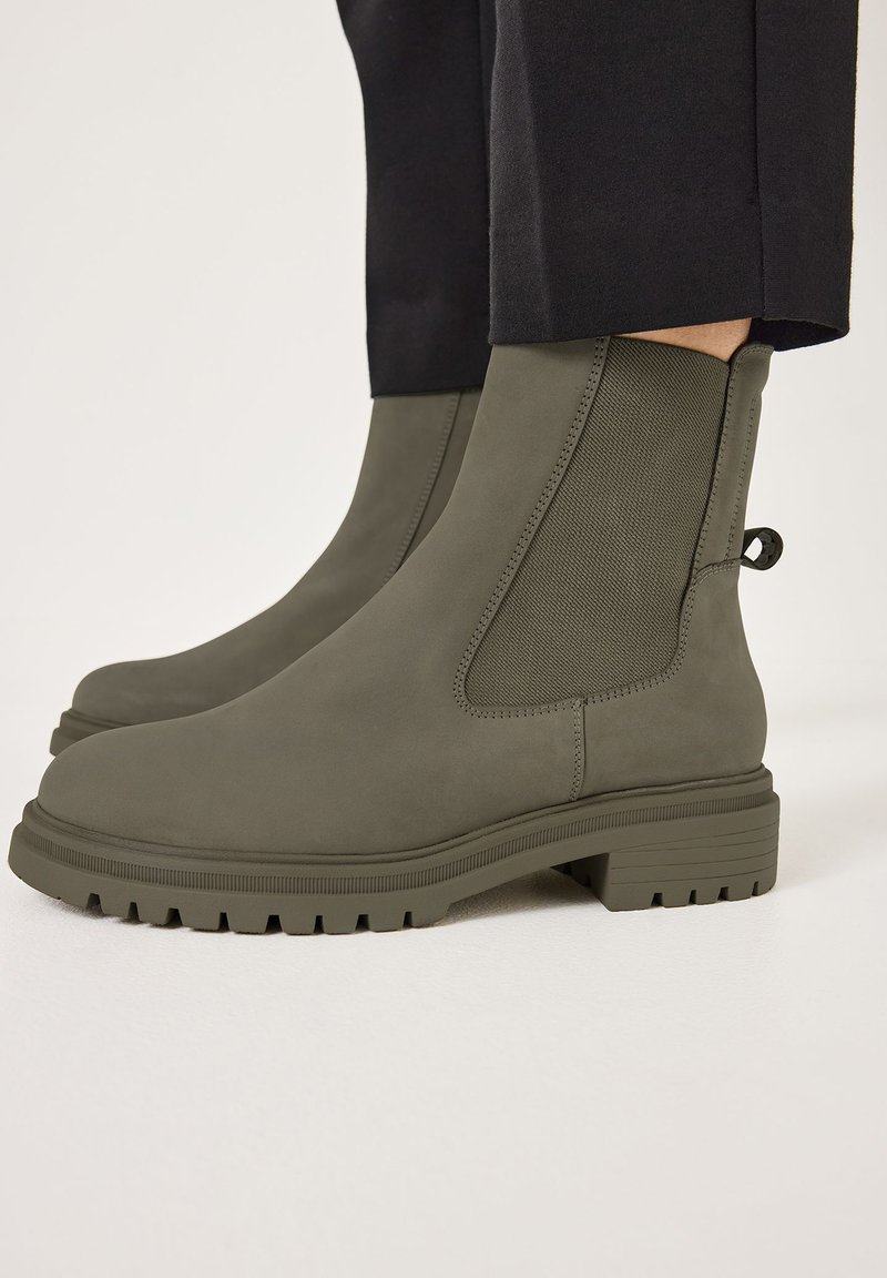 Bottes Chelsea en vert olive foncé, en matériau texturé, avec des panneaux latéraux élastiques, une languette et une semelle épaisse et crantée.