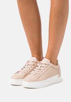 Beżowe skórzane trampki z okrągłym noskiem, sznurowanym przodem i białą gumową podeszwą. Charakteryzują się minimalistycznym designem i teksturowanymi akcentami.