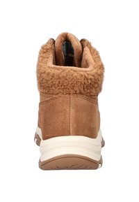 Bruine suède enkellaarzen met een fluffy shearling kraag, een ronde neus en een witte tussenzool. De achterkant heeft stiksels. 
