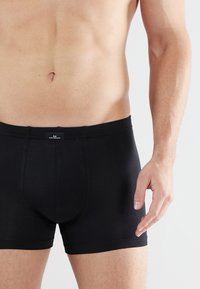 Zwarte katoenen boxershorts met een aansluitend ontwerp, elastische tailleband en geen zichtbare patronen. Soepele textuur met minimale details.