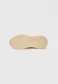 Beige gummisula med cirkulära greppmönster och "ALDO"-logotyp präglad i mitten, isolerad på vit bakgrund.