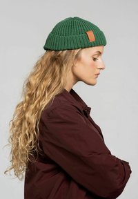 Zielony dzianinowy beanie o prążkowanej fakturze z akcentem ze skórzanej metki. Design jest okrągły i dopasowany, odpoczywa na głowie.