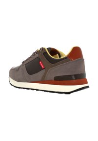 Sneaker in suede grigio con dettagli marroni, fodera gialla e suola bianca. Presenta un design con lacci e un logo sul lato.