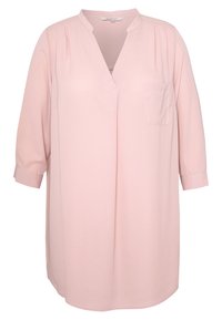 Jasnoróżowa bluzka z dekoltem w kształcie litery V, rękawami o długości trzech ćwiartek i jedną kieszenią na piersi. Wykonana z miękkiego, gładkiego materiału z delikatnymi fałdami.