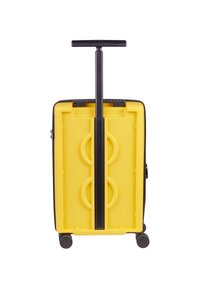 Hard-shell suitcase with a yellow exterior, black handle, and core. Features a vertical handle, smooth wheels, and molded design on the back.