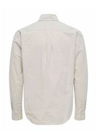 Lyse beige langærmet skjorte med knap-ned krave, ryglæg og knaplukninger ved ærmerne. Glat stof med subtil struktur.