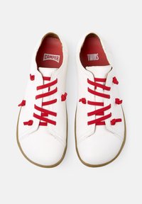 Scarpe in pelle bianca con lacci e dettagli rossi. Punta rotonda, cuciture decorative e suola in gomma. Interno con marchio rosso.