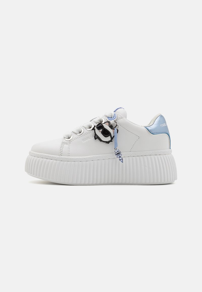 White sneaker with textured, ridged sole, featuring a blue accent at the heel and a pendant detail on the laces. Smooth leather upper.