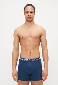 Marineblaue Boxershorts mit einem weißen Bund "BJÖRN BORG". Der Stoff wirkt glatt mit einer taillierten Passform und genähten Details.