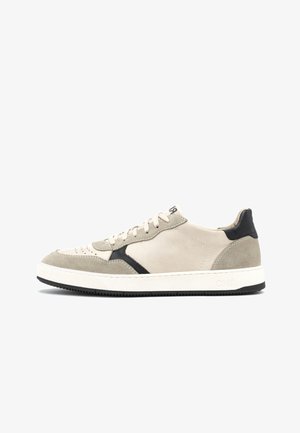 Beżowy zamszowy sneaker z czarnymi akcentami, teksturowaną cholewką, perforowanym noskiem, białą środkową podeszwą i gumową podeszwą zewnętrzną. Posiada płaskie sznurówki i detal z logo.