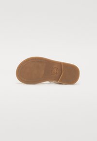 Suela de zapato de goma color bronce con un patrón de ondas, con el texto grabado "¡QUE TENGAS UN BUEN DÍA!". Superficie lisa con una ligera textura y bordes curvados.