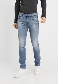 Light blue denim jeans with a slim fit, slightly faded with whiskering details, five pockets, and a standard button closure.