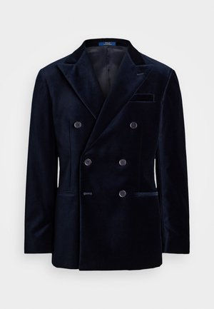 Double-breasted navy velvet blazer with peaked lapels, four front buttons, and side pockets. Smooth texture with subtle sheen and tailored fit.