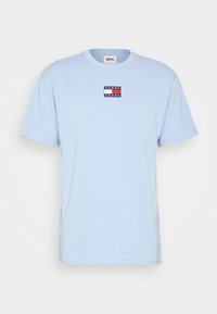 Ljusblå bomulls t-shirt med korta ärmar, med en rektangulär logotyp med "TOMMY JEANS" i svart och vitt.