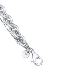 Bracciale in argento con maglie grandi, chiusura a moschettone e un piccolo tag rotondo contrassegnato "925". Finitura liscia e lucida senza decorazioni.