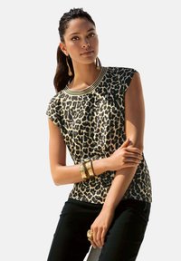 Leopardprint korte mouwen top met een ronde hals en gouden accenten; gedragen met zwarte pants en gouden armbanden. Glad stofoppervlak.