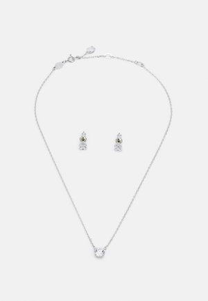 Collana d'argento con un pendente centrale in pietra trasparente; orecchini a bottone abbinati con una piccola pietra trasparente, incastonati in argento.