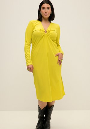 Vestido amarillo de manga larga con escote en V profundo y diseño retorcido en el busto que presenta un corte circular, hecho de tela acanalada.