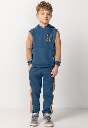 Blaues Kapuzensweatshirt mit braunen Ärmeln und einem "N"-Aufnäher, kombiniert mit passenden blauen Jogginghosen mit braunen seitlichen Streifen und Bündchen.