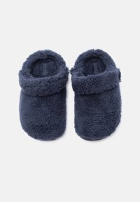 Ζευγάρι ναυτικών μπλε αφράτων παντόφλων με διπλωμένες μανσέτες, απεικονιζόμενες από πάνω σε λευκό φόντο.