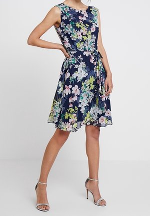 Abito floreale blu navy con colletto tondo, design senza maniche e cintura da annodare. Presenta fiori multicolori e una gonna fluente di lunghezza al ginocchio.