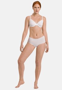 Set di reggiseno e mutandine bianche senza cuciture mostrato su un modello. Il tessuto appare liscio con una leggera lucentezza. Spalline regolabili sul reggiseno.
