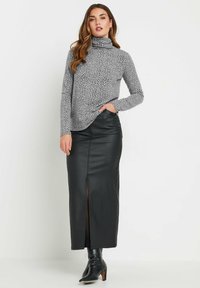 Grijze coltrui met een gestructureerd patroon, gecombineerd met een zwarte leren maxi rok met een split aan de voorkant, en zwarte hielboots.