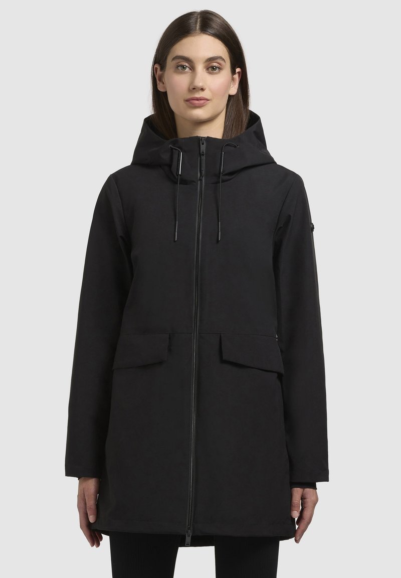 Black waterproof jacket with a hood, featuring a zipper front, two front pockets, and adjustable drawstrings. Smooth texture, knee-length design.
