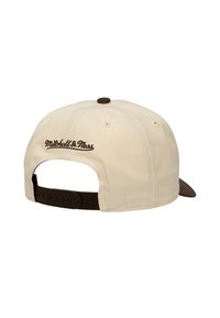 Gorra snapback color crema con visera marrón y correa ajustable. Presenta un logo bordado marrón en el panel trasero.