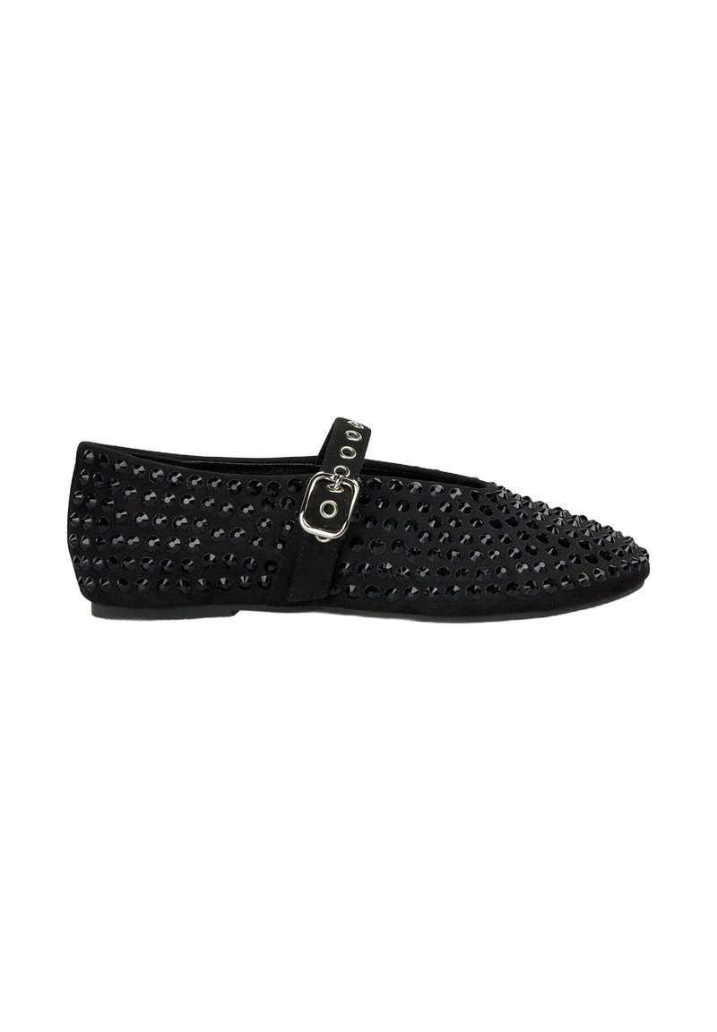 Zapatos planos negros con punta afilada, cubiertos de brillantes tachuelas, con una correa con hebilla de metal en el lateral y una textura suave.