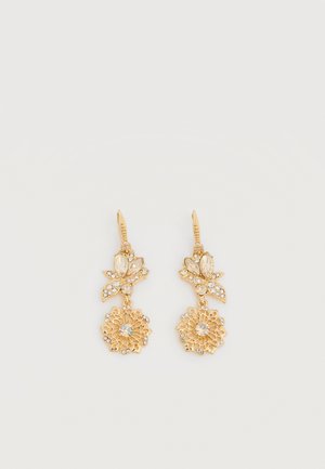Boucles d'oreilles pendantes en ton or avec un motif floral, des cristaux clairs et des détails en filigrane complexes sur un fond blanc uni.