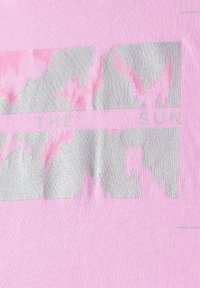 Tissu rose avec un design graphique argenté portant le texte "LE SOLEIL", présentant des motifs ondulés et des nuances variées de rose et de gris.