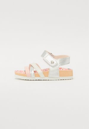 Sandal in argento con più cinturini in materiale lucido, dettagli rosa e una soletta decorata. Suola piatta con bordi bianchi e fibbia regolabile.