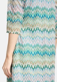 Baumwollkleid mit einem mehrfarbigen Zickzackmuster in Blau, Grün, Pink und Beige. Kurze Ärmel und weicher Stoff.