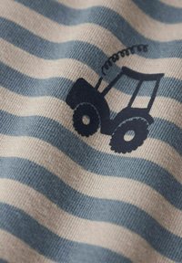 Bomullstyg med växlande blå och beige ränder; har en svart traktor grafik centrerad på tyget.