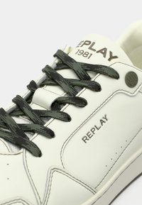 Weißer Sneaker mit schwarzen Schnürsenkeln, "REPLAY 1981" auf der Zunge aufgedruckt und "REPLAY" auf der Seitenpartie geprägt.