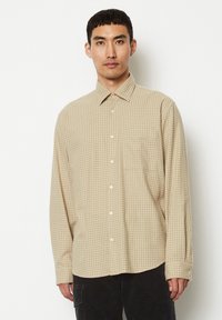 Beige karierte Langarmbluse aus leichtem Stoff, mit einem Button-Down-Kragen, einer Brusttasche und abgerundetem Saum.