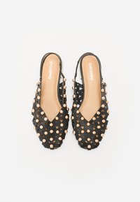 Scarpe slingback nere con un design a taglio triangolare, dotate di borchie metalliche e una soletta beige liscia. Logo del marchio sulla soletta.
