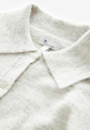 Hellgraues, weiches Wollstrick-Polohemd mit Kragen, Knopfleiste und subtiler Textur. Das Etikett trägt die Aufschrift "N. PREMIUM COLLECTION."