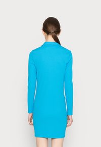 Vestido de manga longa em azul brilhante, feito de tecido canelado. Design justo com colarinho, terminando acima dos joelhos, textura suave sem padrões.
