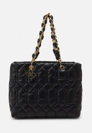 Czarna pikowana skórzana torebka na ramię z złotymi łańcuszkami splecionymi ze skórą oraz złotym logo marki zawieszonym na jednym uchwycie.
