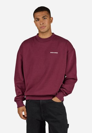 Maroon sweatshirt with ribbed crew neck and cuffs, featuring a small white logo on the chest. Made from soft fleece material.