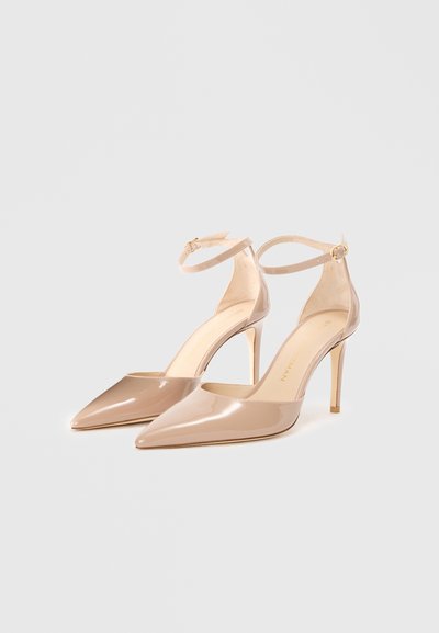 Cizme cu toc înalt din piele patentată, nude, cu vârf ascuțit, curele subțiri la gleznă și tocuri stilettos de 10 cm. Textură netedă cu accente minimale.