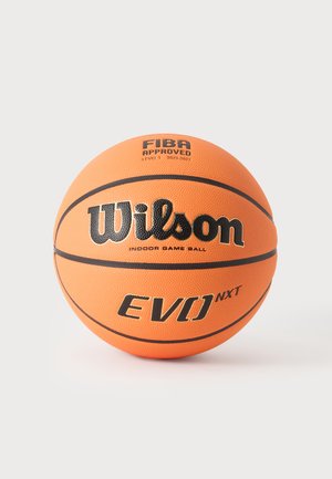 Baloncesto naranja Wilson EVO NXT con texto y líneas negras sobre un fondo claro y liso.