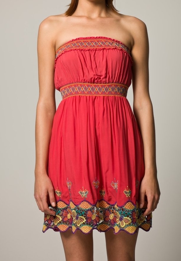 Vestido sin mangas color coral con cinturilla elástica. Presenta vibrantes bordados florales en el dobladillo y un intrincado detalle en hilo multicolor.